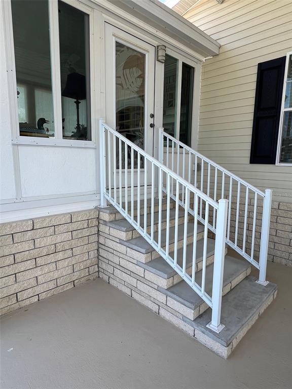A set of concrete steps with white metal railings leads to a glass door — 29250 US HIGHWAY 19 N UNIT 434, CLEARWATER, FL