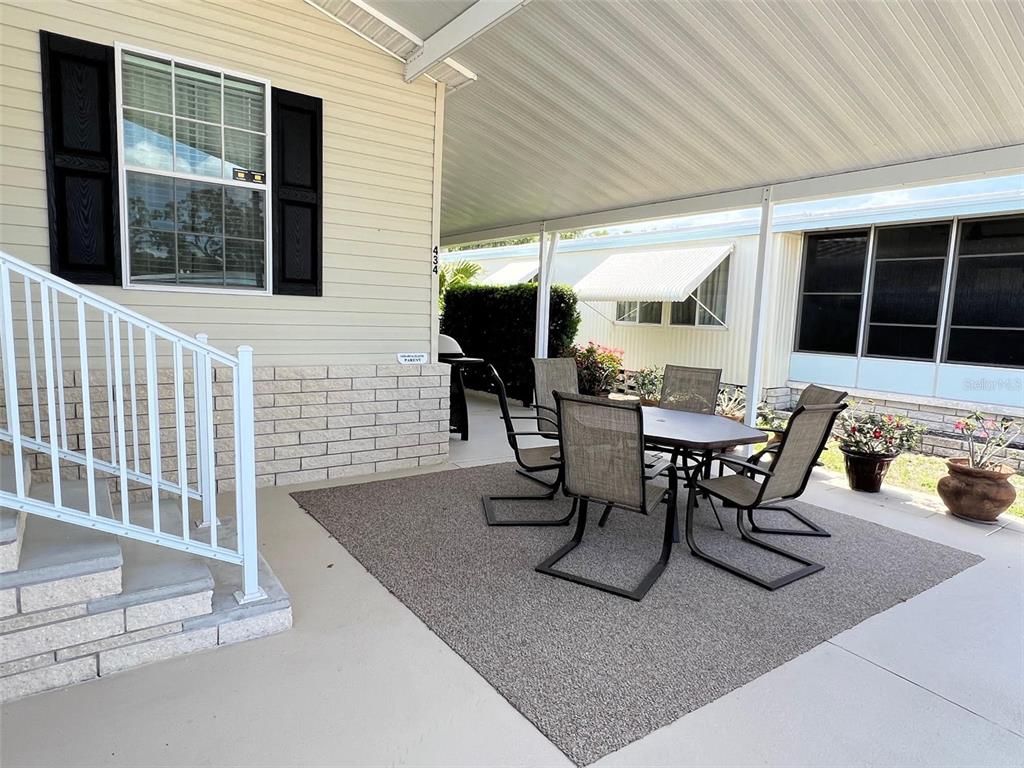 A covered patio features a dining set on a rug next to a house exterior — 29250 US HIGHWAY 19 N UNIT 434, CLEARWATER, FL
