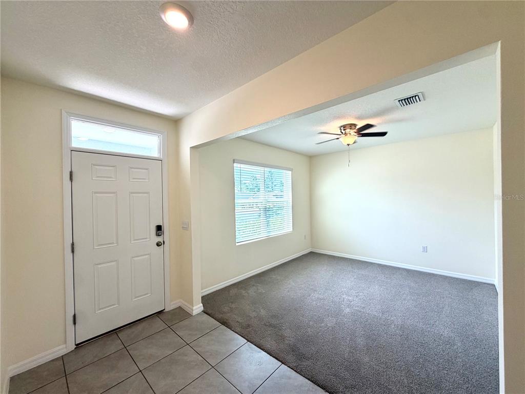 An entryway with tile flooring leads into a carpeted room with a ceiling fan — 39 HICKORY COURSE WAY, OCALA, FL