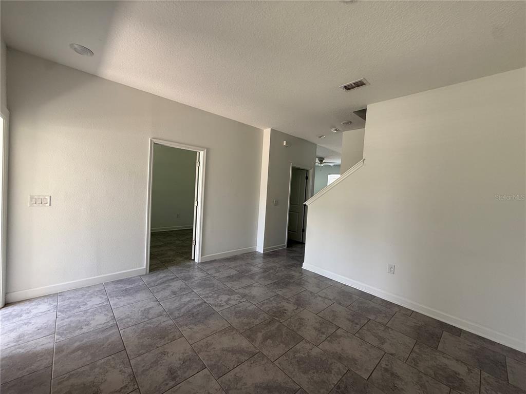 An interior room features gray tile flooring, white walls, and doorways leading to other spaces — 5647 QUIET PALM LOOP, ST CLOUD, FL