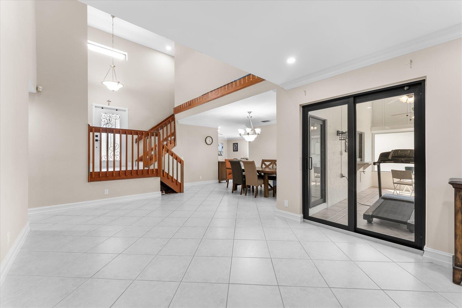 A bright, open-concept living area features white tile flooring, a wooden staircase, and sliding doors — 2116 Austin, Weston FL 33326, WESTON, FL