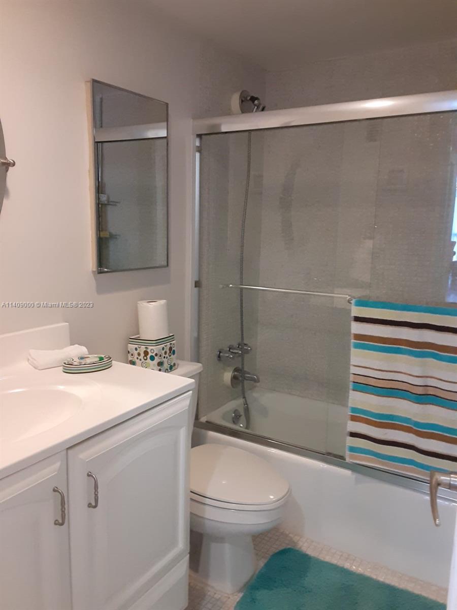 A bathroom features a white vanity, a toilet, and a shower-tub combination with glass doors — 3801 S Ocean Dr # 5O, Hollywood FL 33019, HOLLYWOOD, FL