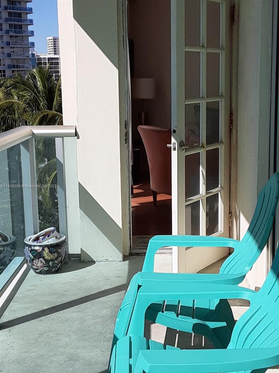 A balcony with two turquoise chairs and a floral planter overlooks a city skyline — 3801 S Ocean Dr # 5O, Hollywood FL 33019, HOLLYWOOD, FL