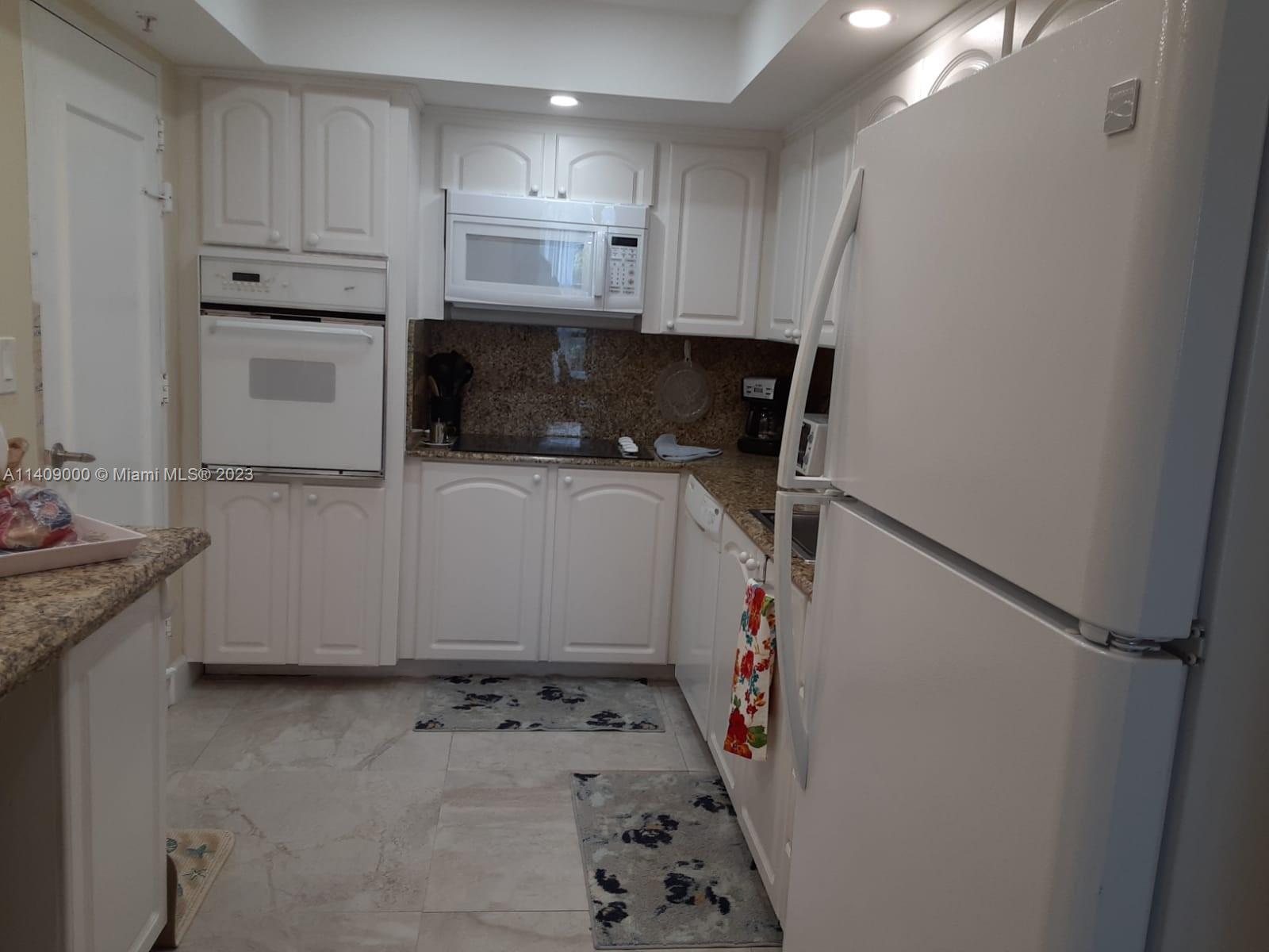 A kitchen features white cabinets, granite countertops, a wall oven, and a white refrigerator — 3801 S Ocean Dr # 5O, Hollywood FL 33019, HOLLYWOOD, FL