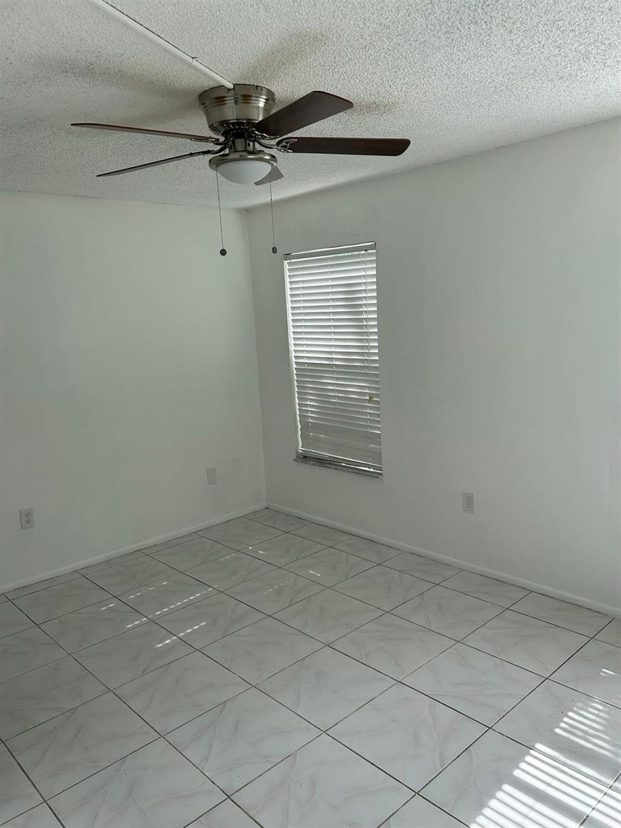 An empty room with white walls, tiled flooring, a ceiling fan, and a single window — 3405 Knolls Road, Miramar FL 33025, MIRAMAR, FL