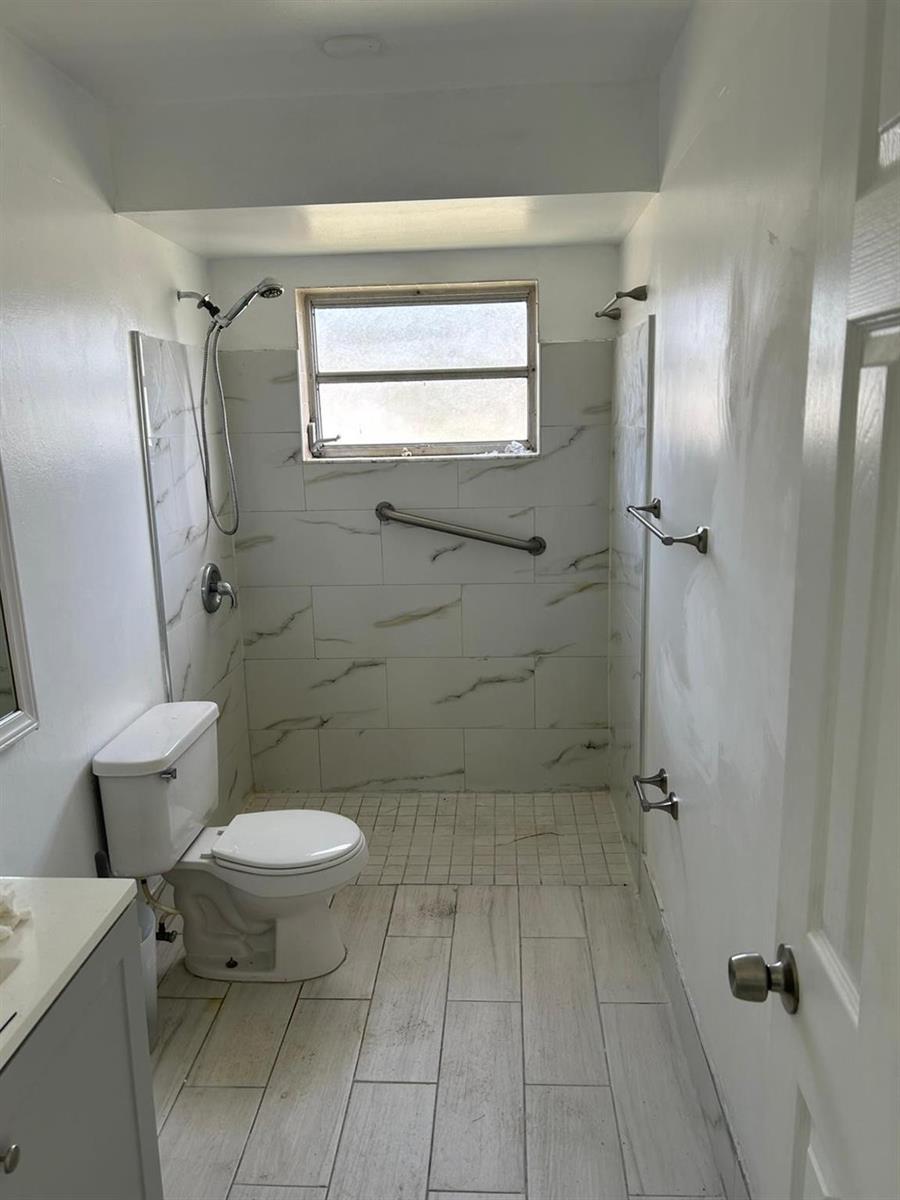A bathroom features a walk-in shower with white marble-look tile, a toilet, and light flooring — 3405 Knolls Road, Miramar FL 33025, MIRAMAR, FL