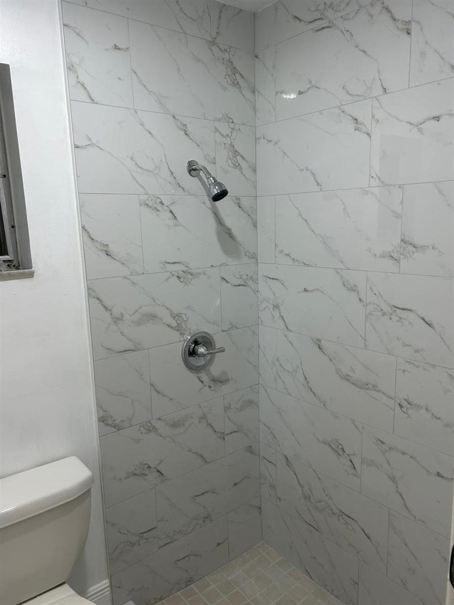 A shower stall features white marble-look wall tiles and a chrome shower head and handle — 3405 Knolls Road, Miramar FL 33025, MIRAMAR, FL