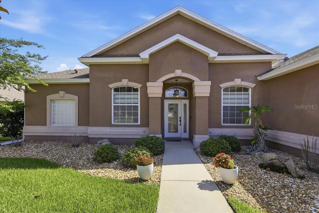 A tan stucco house features a central entryway with a glass door and arched window — 58 BUTTERFIELD DRIVE, PALM COAST, FL