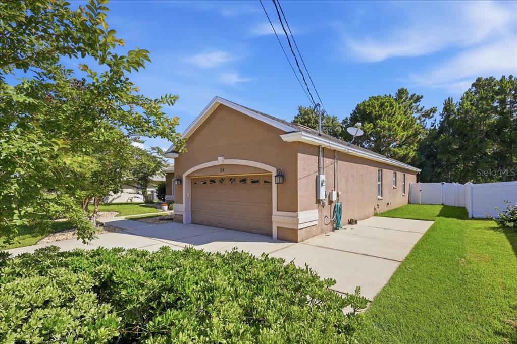 A tan single-story house with a two-car garage and a concrete driveway — 58 BUTTERFIELD DRIVE, PALM COAST, FL
