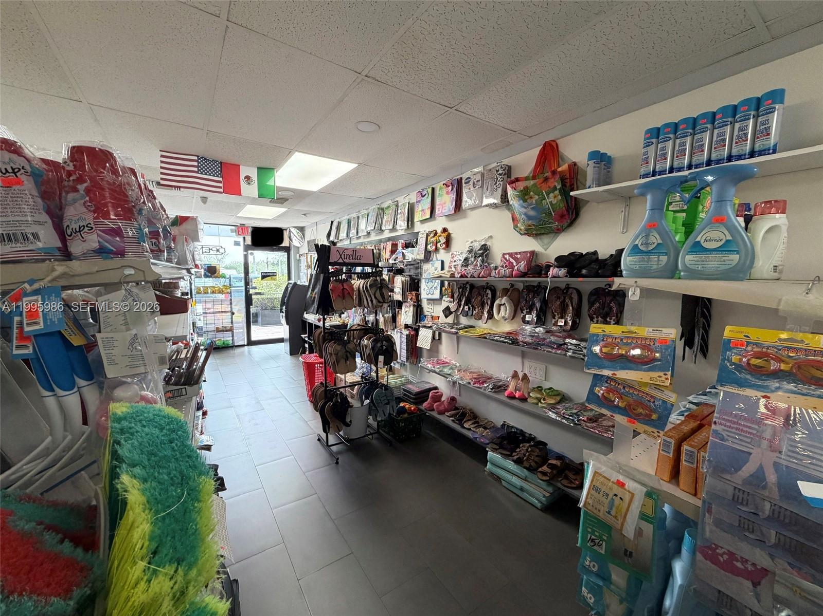 A retail store interior features shelves stocked with various household goods, footwear, and cleaning supplies — GROCERY STORE FOR SALE, Miami FL 33155, MIAMI, FL