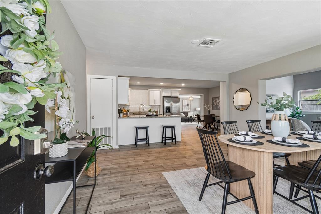 A dining area with a wooden table leads into a kitchen with white cabinets — 10746 109TH STREET, SEMINOLE, FL