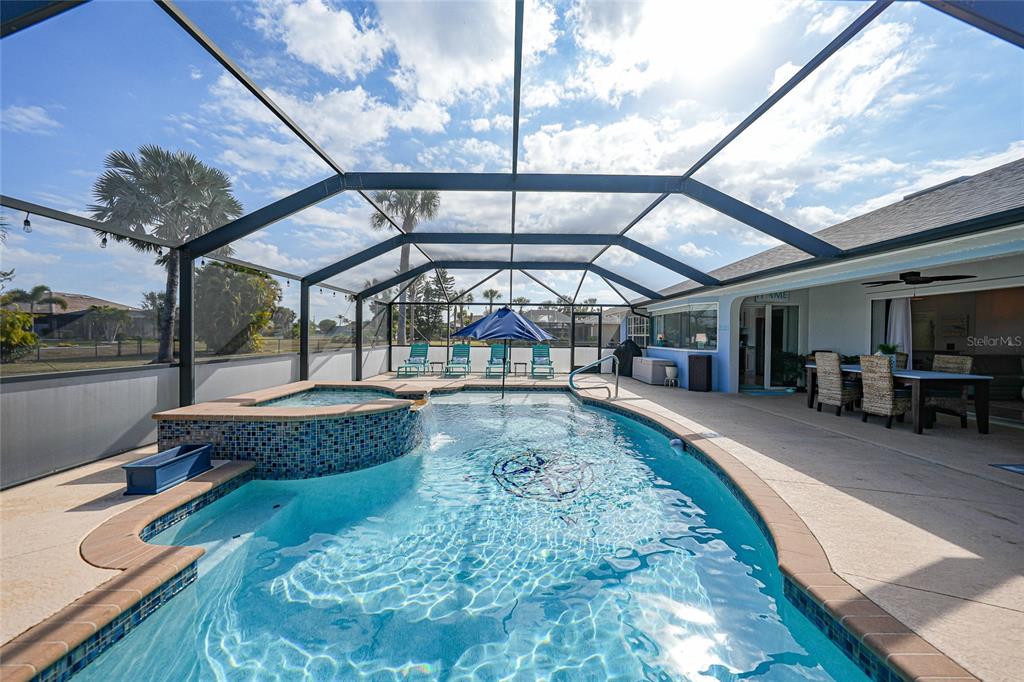 A screened-in patio features a swimming pool with an attached hot tub and dining area — 600 ROYAL POINCIANA, PUNTA GORDA, FL