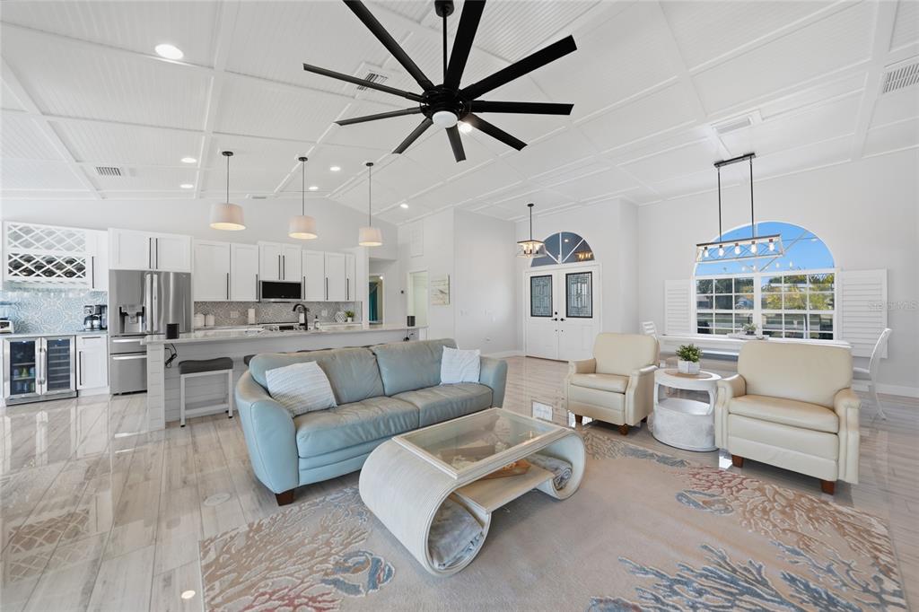 An open-concept living room and kitchen feature white cabinetry, tile flooring, and a large ceiling fan — 600 ROYAL POINCIANA, PUNTA GORDA, FL