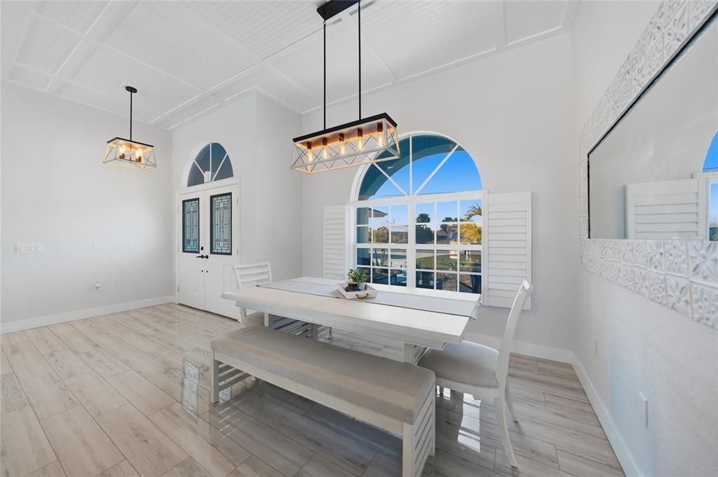 A dining room with a white table, bench, chairs, pendant lighting, and arched windows — 600 ROYAL POINCIANA, PUNTA GORDA, FL