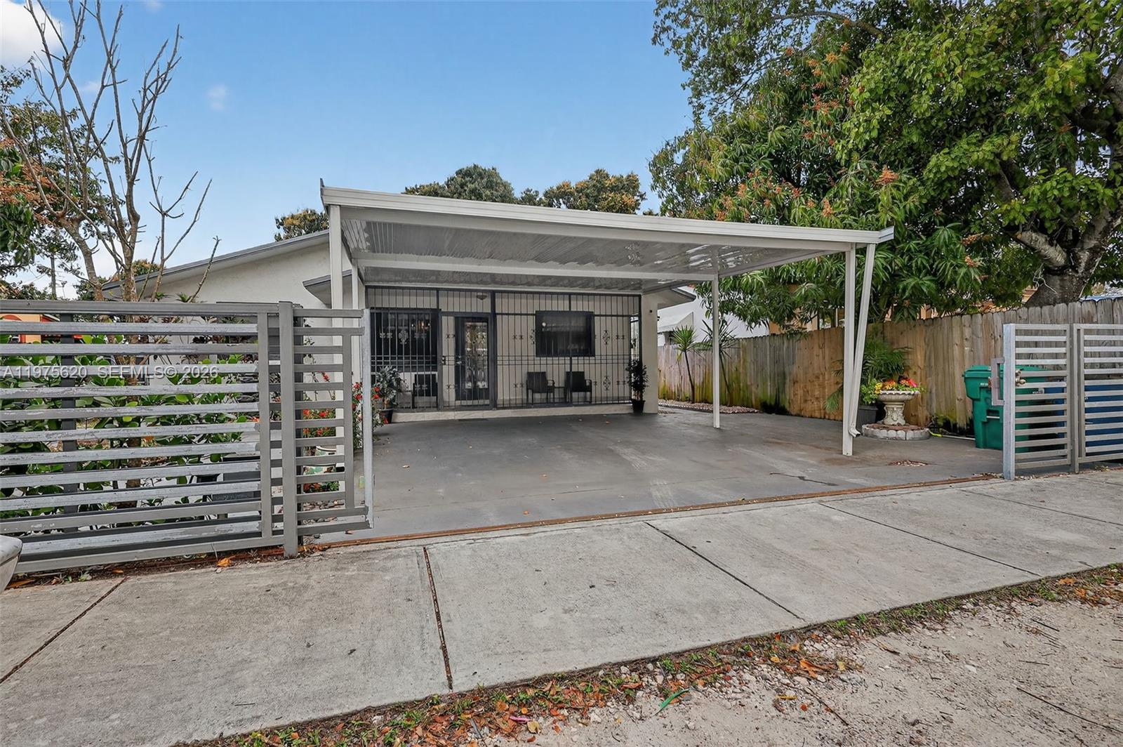 A single-story house features a concrete driveway, a metal carport, and a gated front entrance — 834 NW 115th St, Miami FL 33168, MIAMI, FL