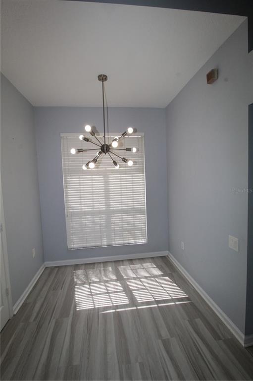 An empty dining area features light gray walls, wood-look flooring, and a modern sputnik chandelier — 6031 BAY VALLEY COURT, ORLANDO, FL