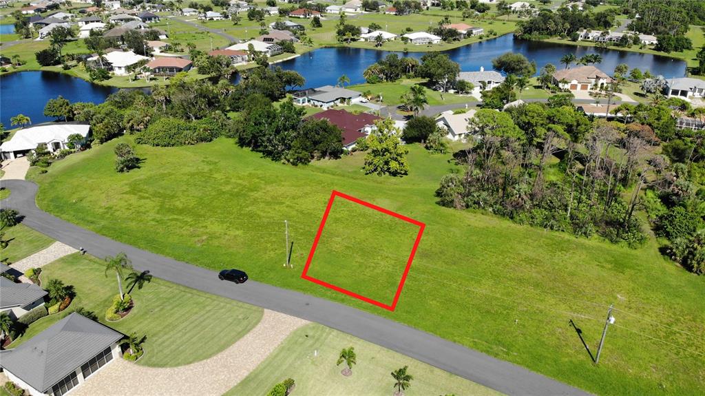 An aerial view shows a vacant, grassy residential lot outlined in red along a paved road — 17512 CUILLAGAN COURT, PUNTA GORDA, FL