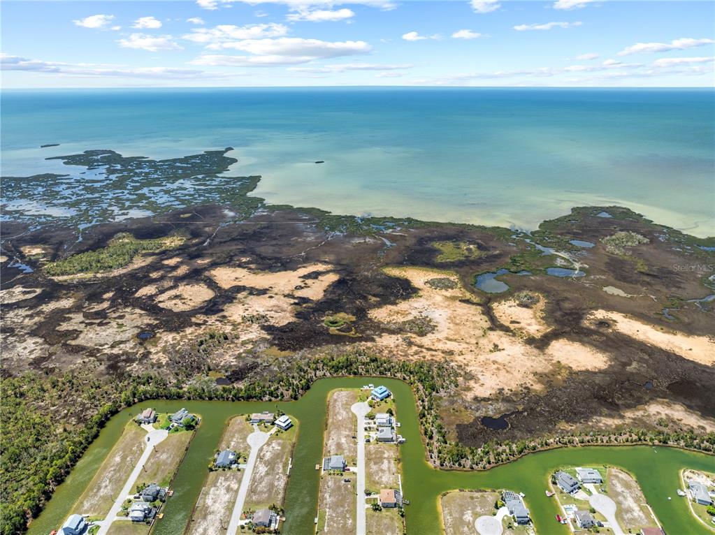An aerial view shows waterfront houses situated on canals adjacent to a large coastal marsh — 3336 CROAKER DRIVE Lot 36, HERNANDO BEACH, FL