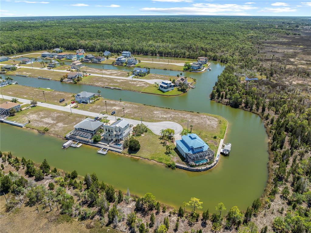 An aerial view shows several houses situated along man-made canals surrounded by dense forest — 3336 CROAKER DRIVE Lot 36, HERNANDO BEACH, FL