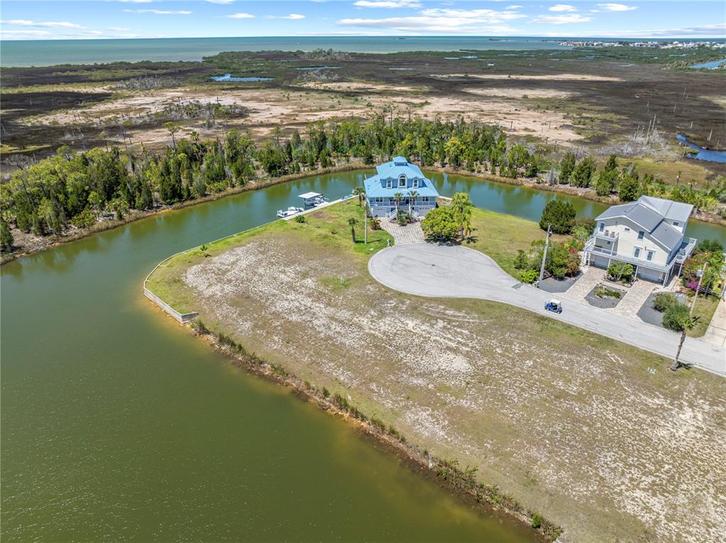 An aerial view shows two houses situated on a peninsula surrounded by a canal — 3336 CROAKER DRIVE Lot 36, HERNANDO BEACH, FL