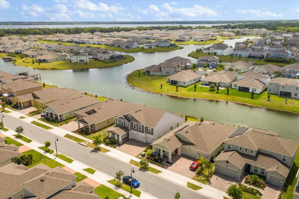 An aerial view shows a suburban neighborhood with houses surrounding a winding lake — 4937 LOTTA COURT, ST CLOUD, FL