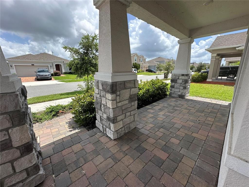 A covered front porch features stone-based columns and multi-colored paver flooring — 4937 LOTTA COURT, ST CLOUD, FL
