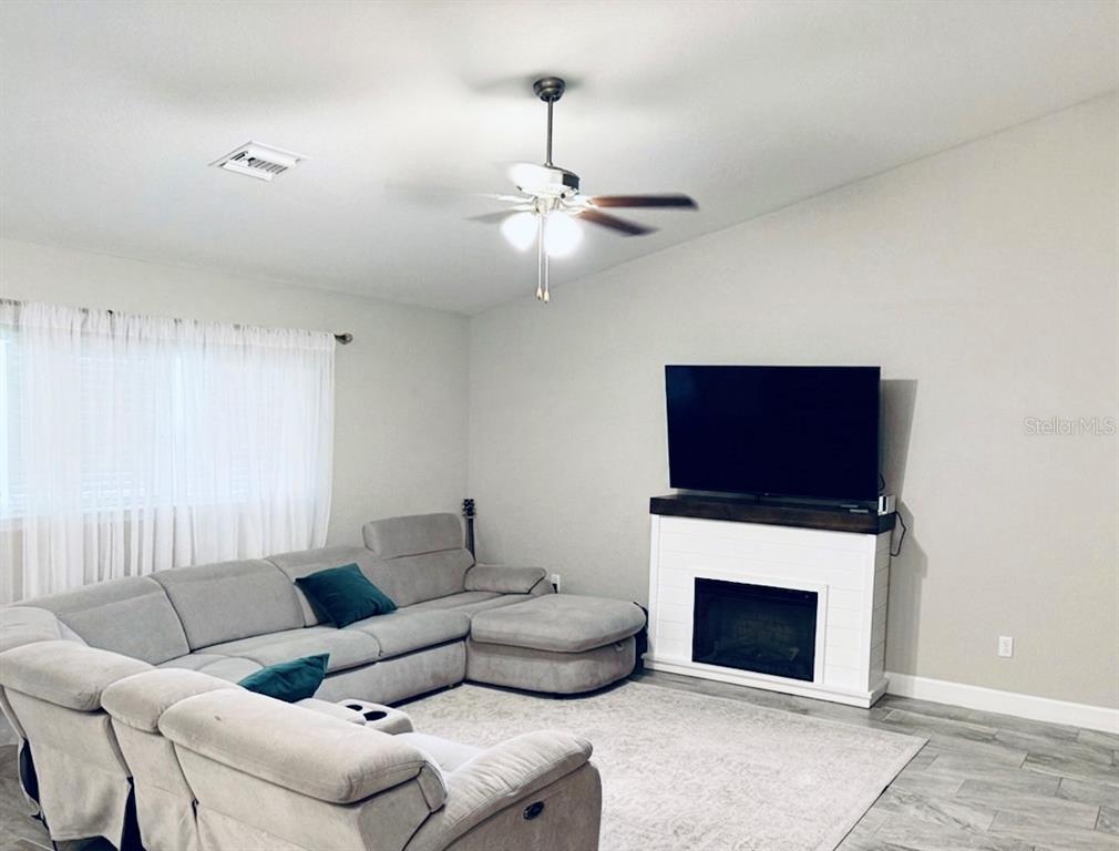 An open-concept kitchen features white cabinetry, granite countertops, a large island with bar seating, and tile flooring — 5601 SW 117TH LANE ROAD, OCALA, FL