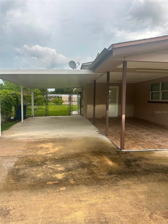 A concrete carport and a covered patio with tiled flooring are attached to a house — 2106 AVALON ROAD, SEBRING, FL