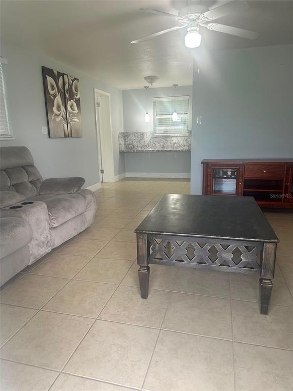 A living room with tile floors, a gray sofa, and a dark coffee table — 2106 AVALON ROAD, SEBRING, FL