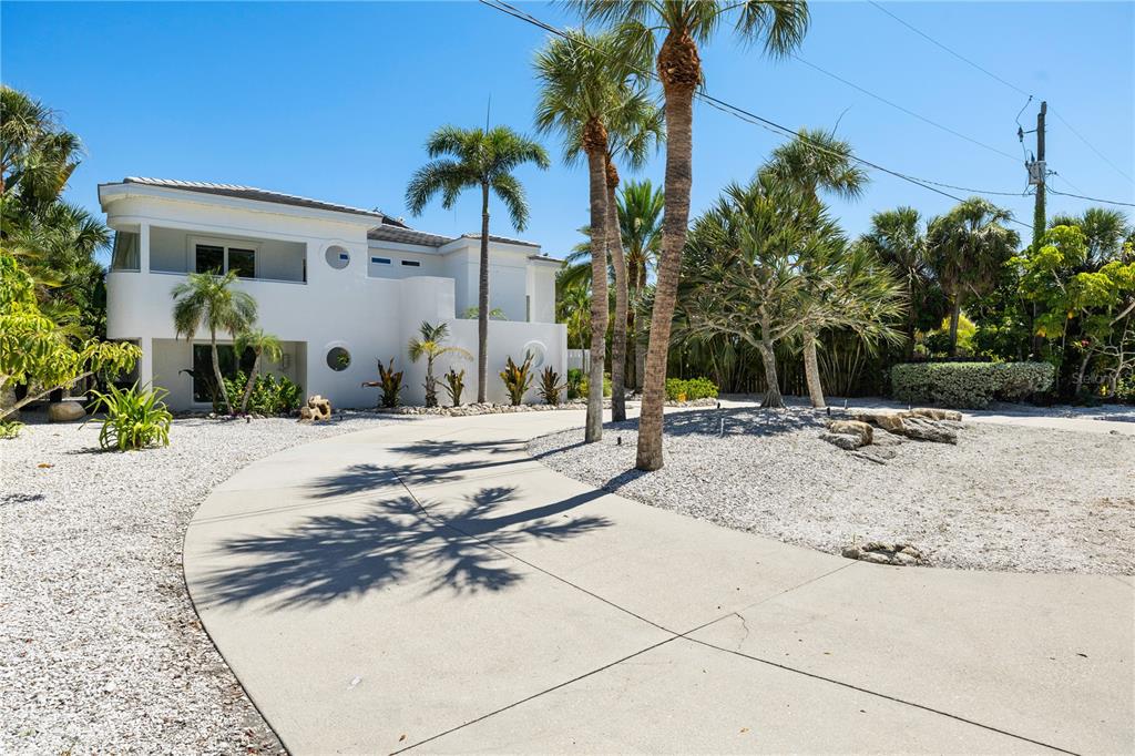 A white two-story house with a curved facade sits behind a concrete driveway and landscaping — 412 TREASURE BOAT WAY, SARASOTA, FL