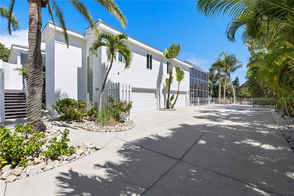 A white two-story house features a concrete driveway, a two-car garage, and palm trees — 412 TREASURE BOAT WAY, SARASOTA, FL