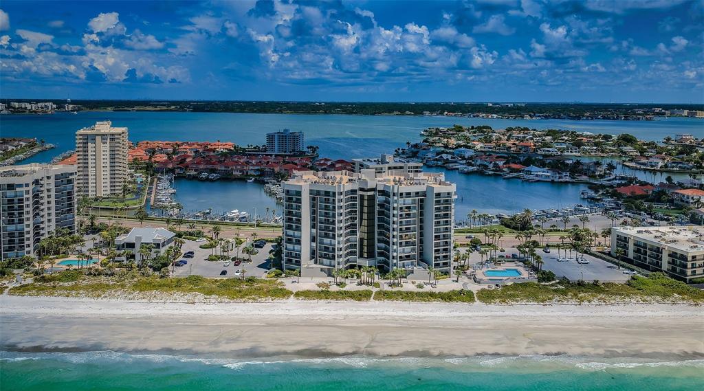 An aerial view of a beachfront condominium complex with a pool and surrounding coastal homes — 1660 GULF BOULEVARD UNIT 208, CLEARWATER BEACH, FL