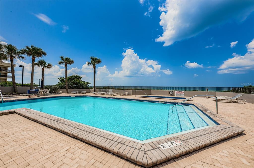 An outdoor swimming pool with a shallow end and lounge chairs overlooks the ocean — 1660 GULF BOULEVARD UNIT 208, CLEARWATER BEACH, FL