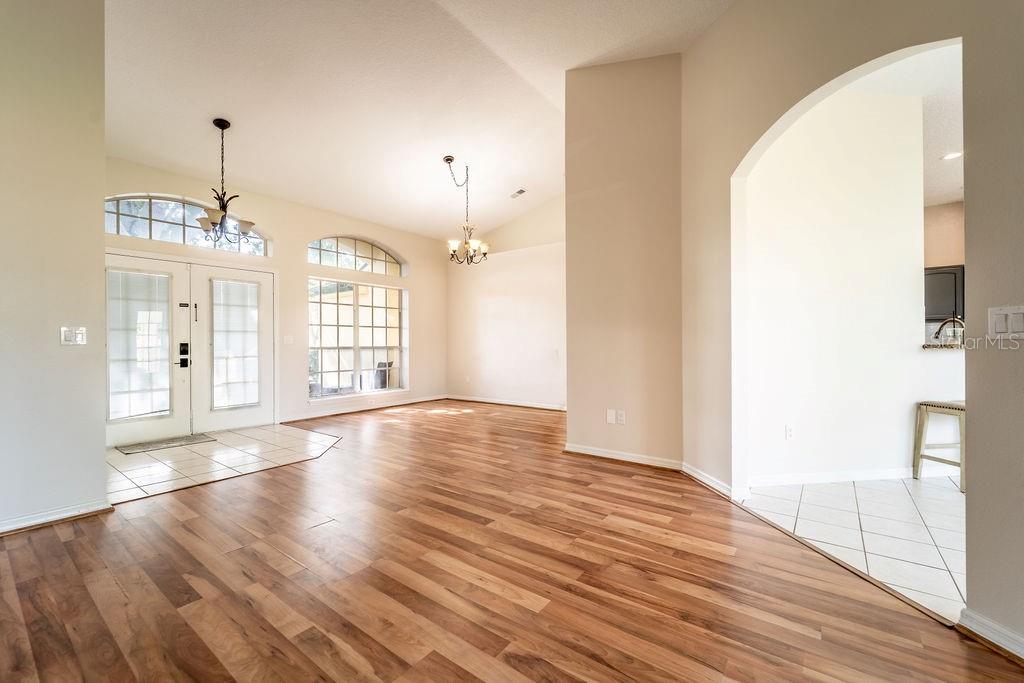 A living room with wood-look flooring, a sliding glass door, and an adjacent kitchen area — 107 NEEDLEWOOD LOOP, DEBARY, FL