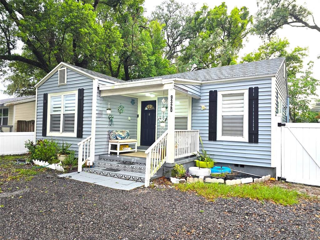 A light blue house with white trim, a front porch, and a gravel driveway — 9320 N ELMER STREET, TAMPA, FL