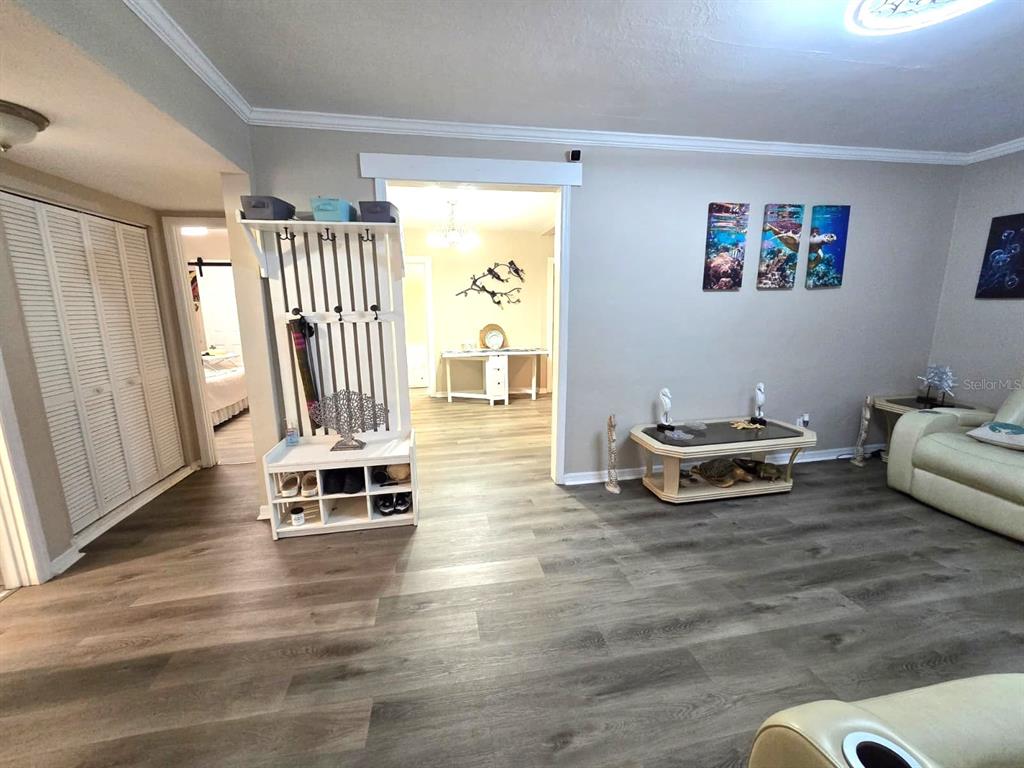 A living room features wood-look flooring, a white coat rack, and a coffee table — 9320 N ELMER STREET, TAMPA, FL