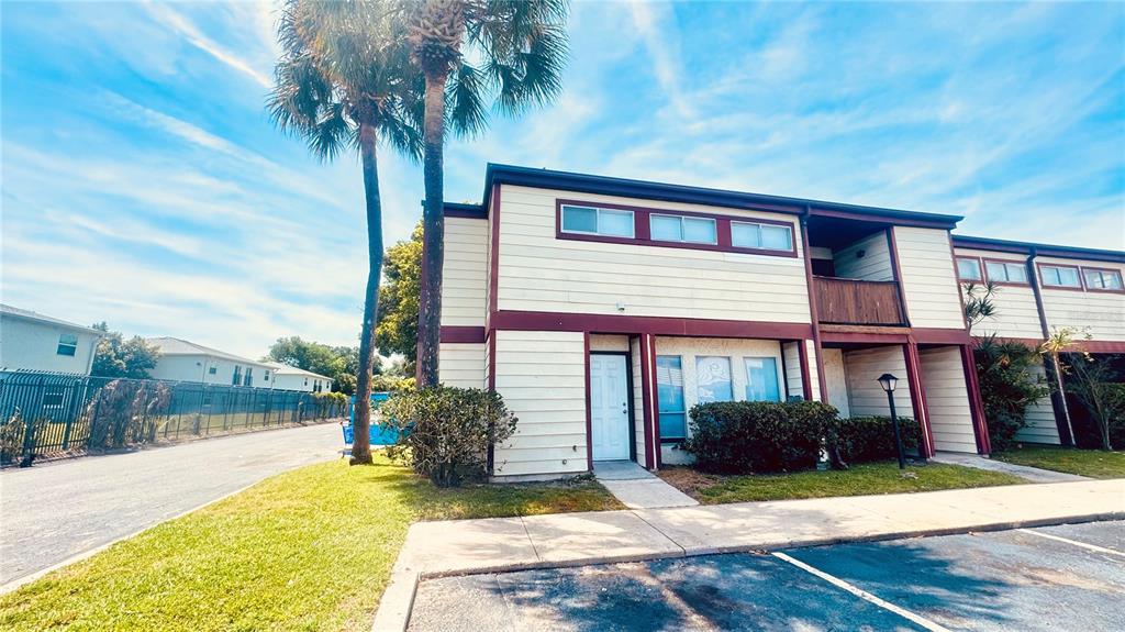 A two-story apartment building features light-colored siding, dark trim, and a palm tree out front — 4016 WOODFERN DRIVE UNIT B8, ORLANDO, FL