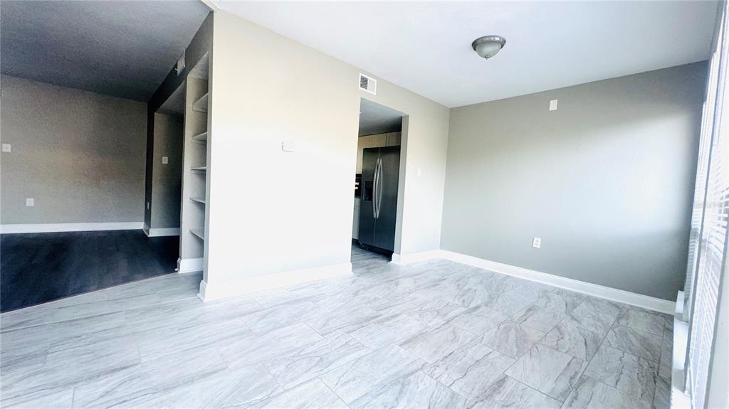A dining area features light gray walls, marble-look tile flooring, and built-in wall shelving — 4016 WOODFERN DRIVE UNIT B8, ORLANDO, FL