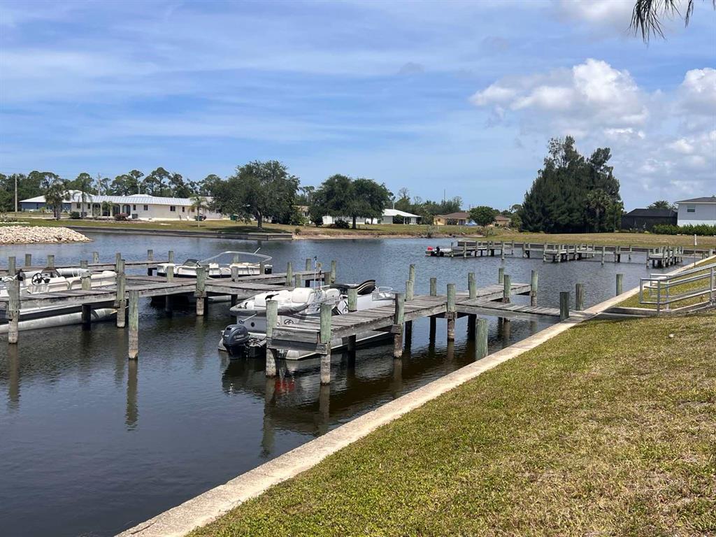 A canal view features wooden boat docks with several pontoon boats moored in the water — 163 MARINER LANE, ROTONDA WEST, FL