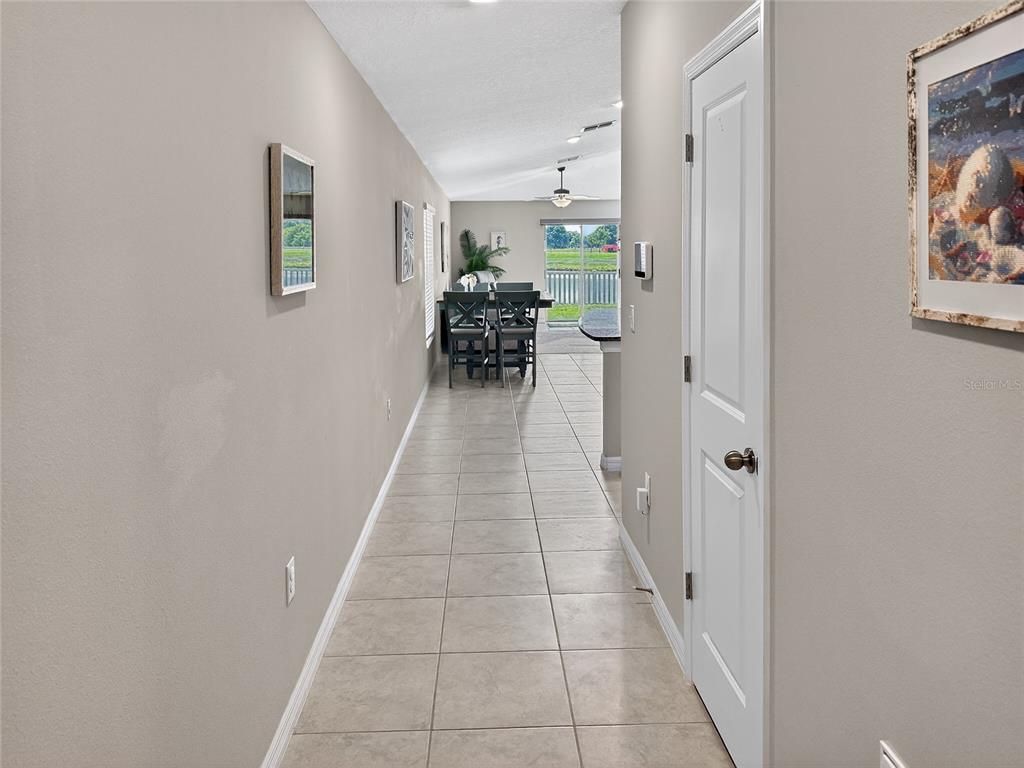A tiled hallway leads past a closed door toward a dining area and patio view — 14441 TOUCH GOLD LANE, SUN CITY CENTER, FL