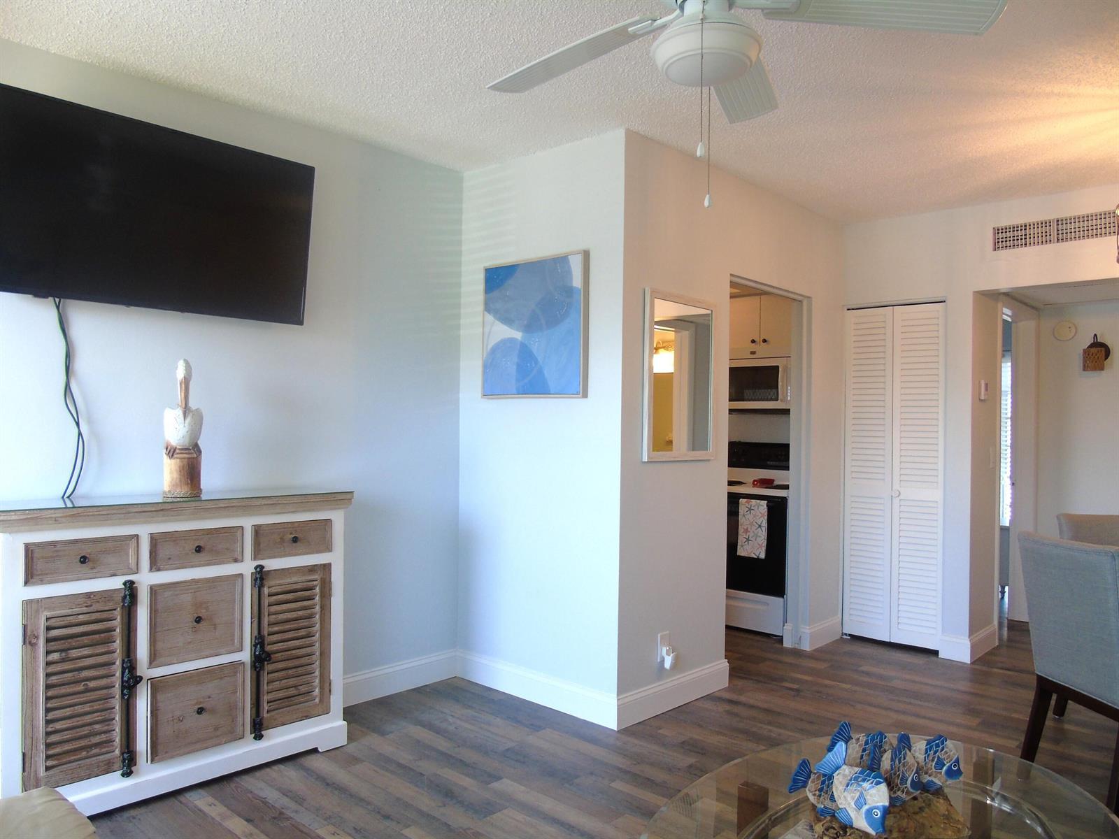 A living room features a television, a wooden cabinet, a ceiling fan, and wood flooring — 309 Circle Drive S # 204, Boynton Beach FL 33435, BOYNTON BEACH, FL