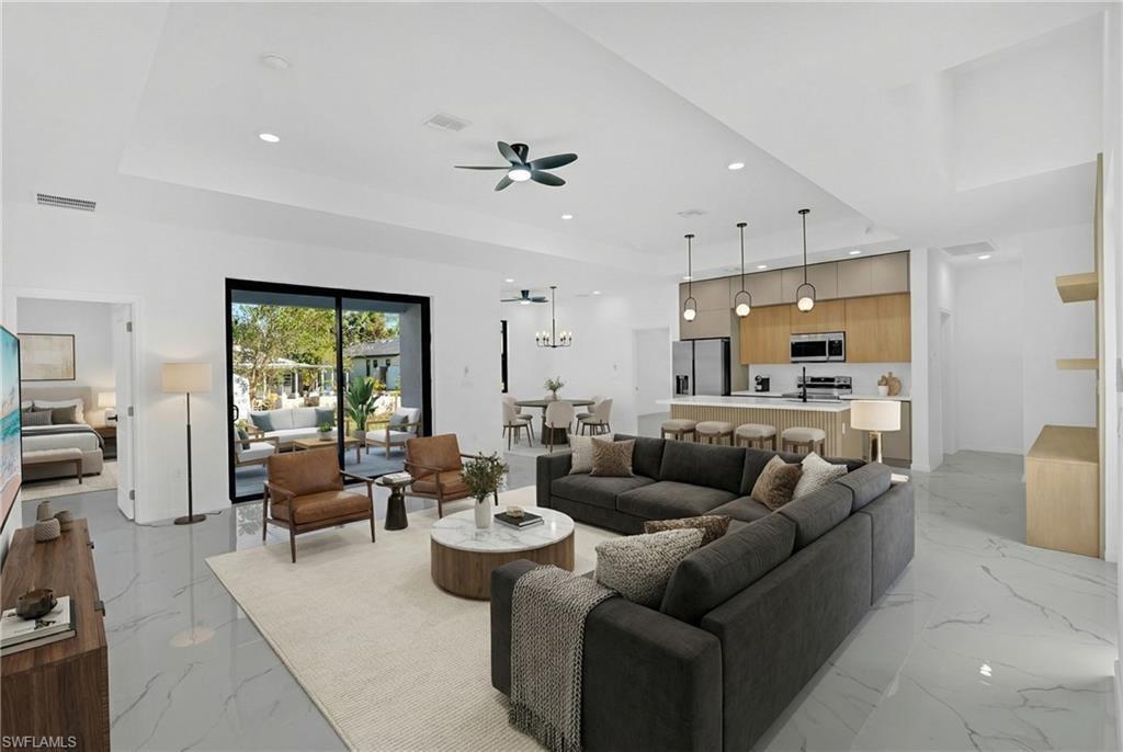 A modern open-concept living room and kitchen featuring marble-look tile floors and sliding glass doors — 2909 9th Street, Lehigh Acres FL 33971, LEHIGH ACRES, FL