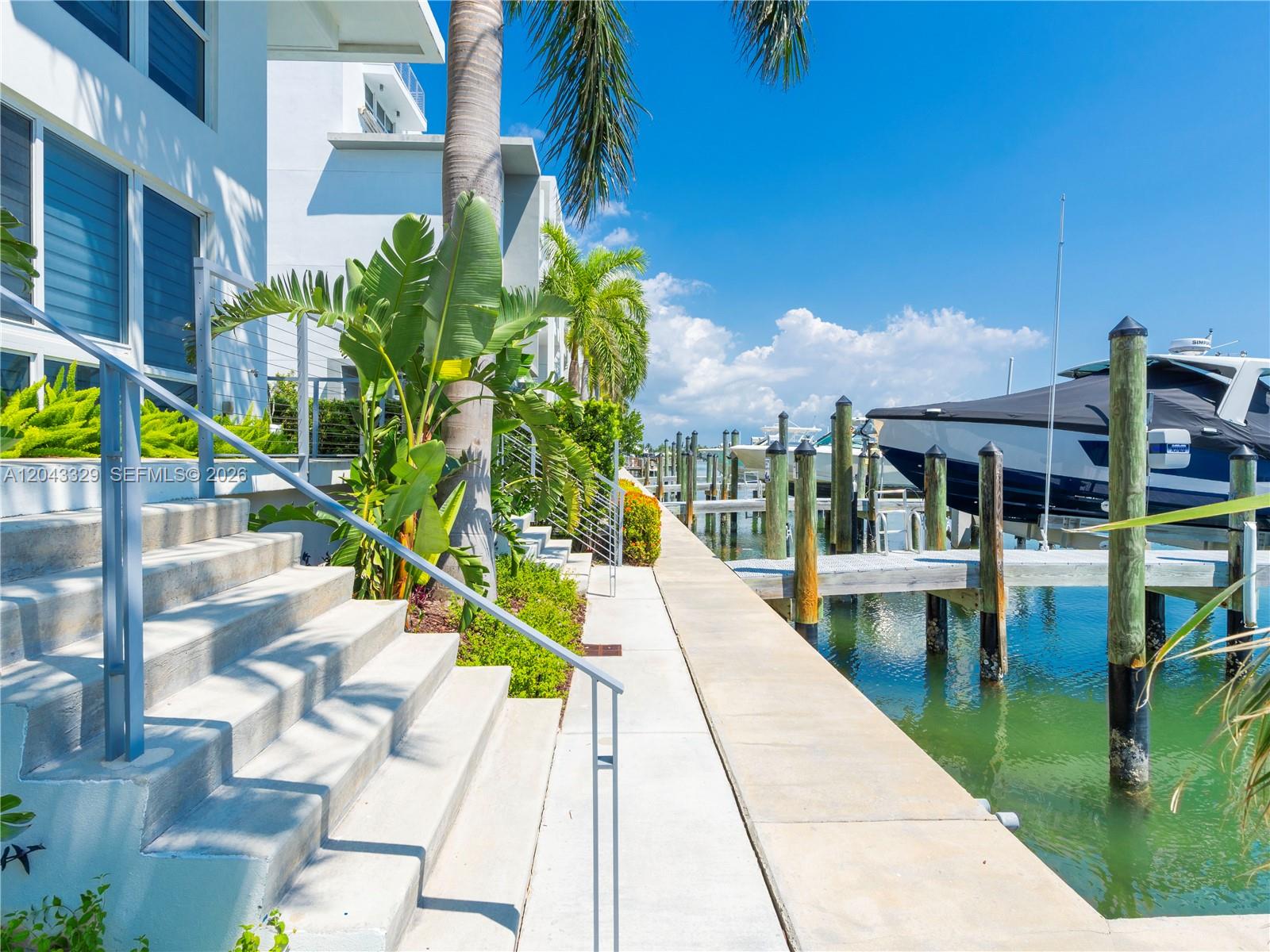 Concrete stairs lead to a waterfront walkway with boat slips and a docked yacht — 51 N Shore Dr # 51, Miami Beach FL 33141, MIAMI BEACH, FL