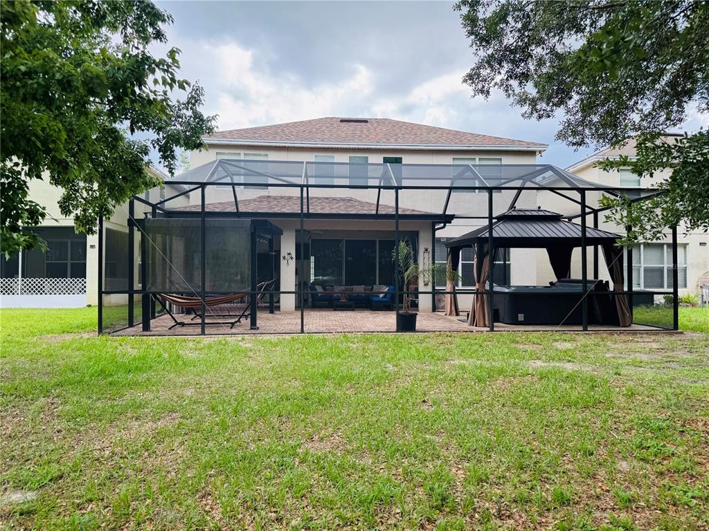 A two-story house features a screened-in patio with a hot tub and a hammock — 992 NODDING SHADE DRIVE, BROOKSVILLE, FL