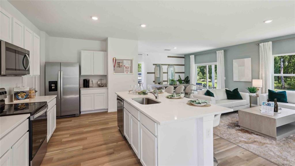 An open-concept kitchen with a white island and stainless steel appliances overlooks a living area — 24349 NW 10TH ROAD, NEWBERRY, FL