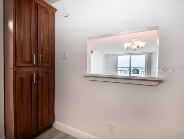 A tall wooden cabinet stands next to a wall opening that overlooks a room with a chandelier — 7401 BAY ISLAND DRIVE S UNIT 237, SOUTH PASADENA, FL