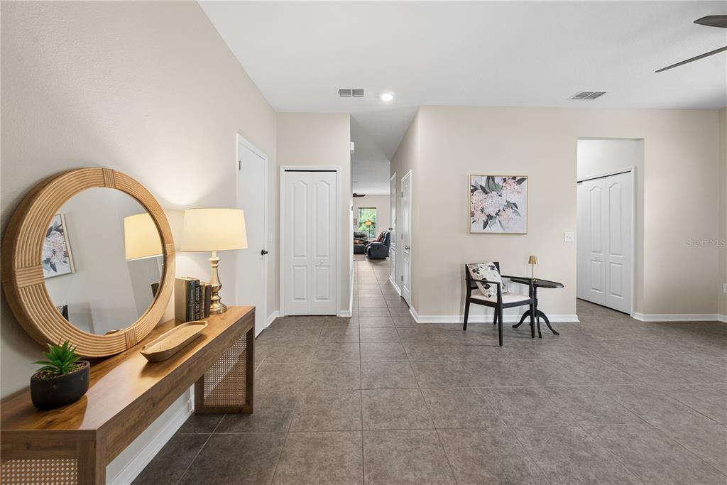 A tiled entryway features a wooden console table with a round mirror and a small seating area — 14369 NW 159TH PLACE, ALACHUA, FL