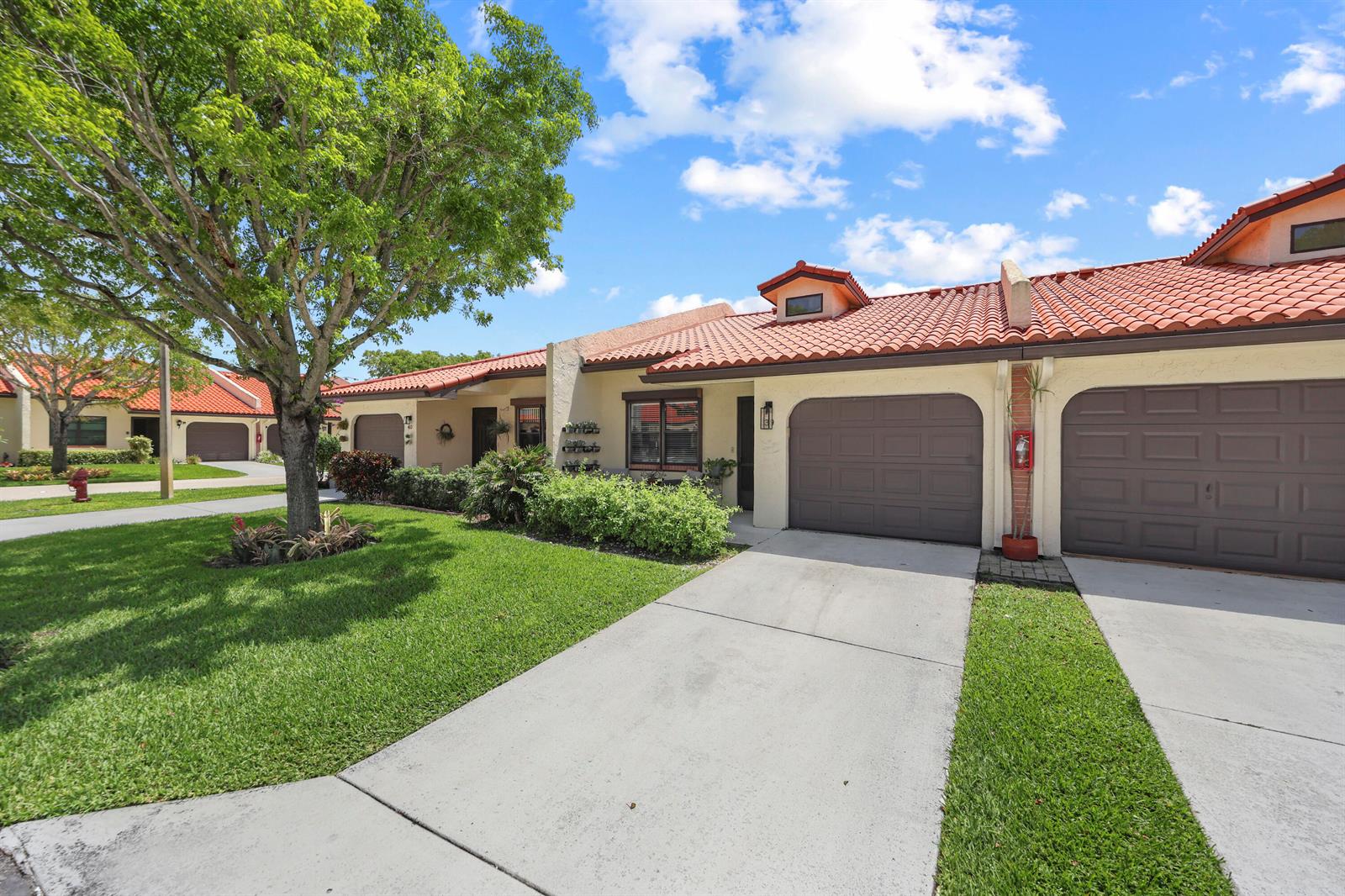 A row of single-story townhomes features brown garage doors, red tile roofs, and green lawns — 39 Bethesda Park Circle # L39, Boynton Beach FL 33435, BOYNTON BEACH, FL
