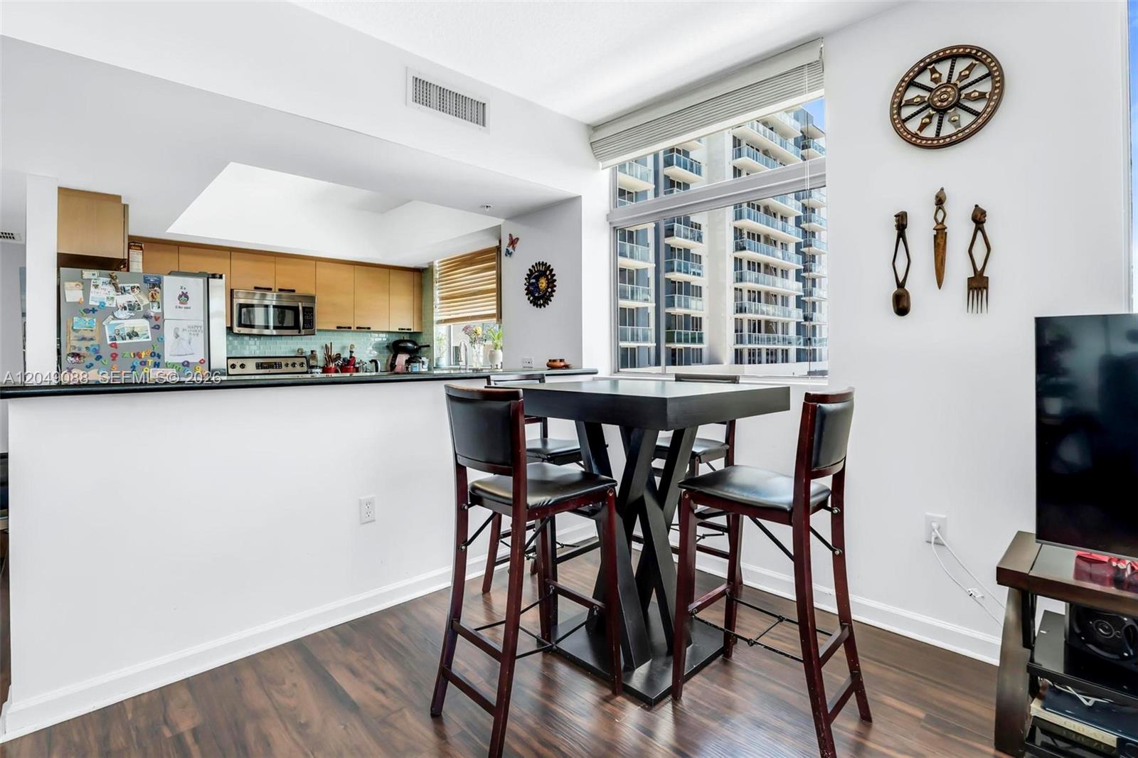 A dining area with a square table and stools sits before a kitchen and window — 140 S Dixie Hwy # 501, Hollywood FL 33020, HOLLYWOOD, FL