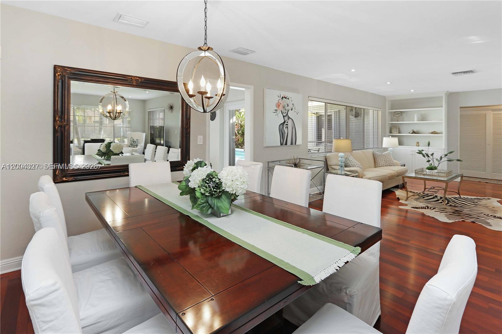 A dining room with a dark wood table and white chairs sits beside a living area — 1147 Buchanan St, Hollywood FL 33019, HOLLYWOOD, FL